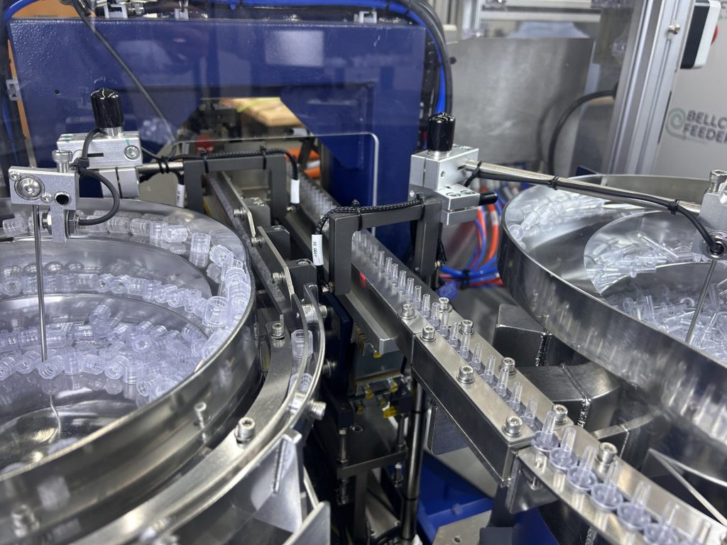Clear molded parts circulating in a Bellco stainless bowl feeding an automated assembly station