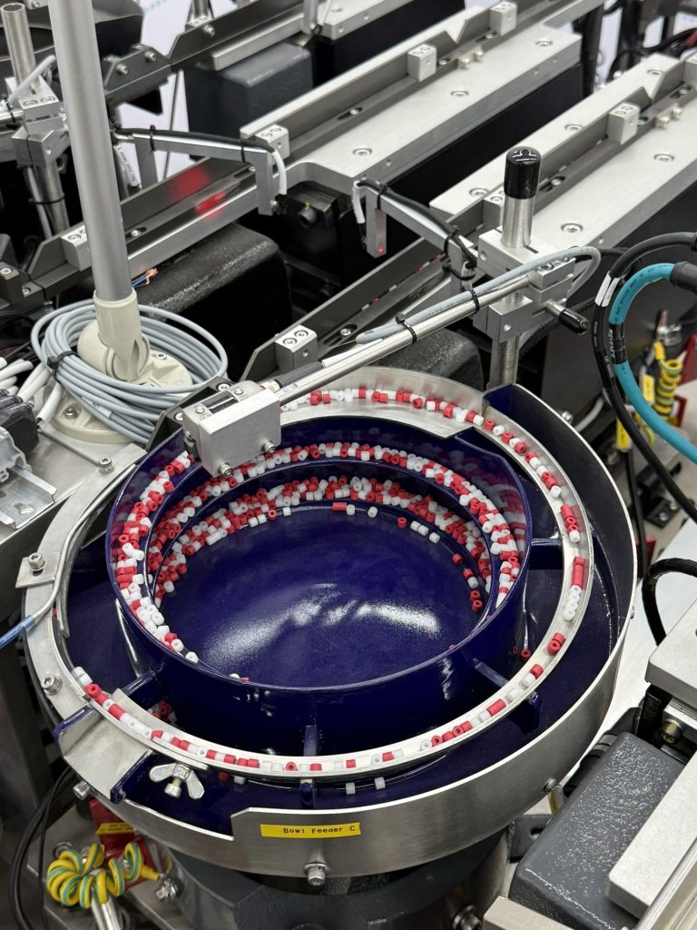 Red and white plastic parts circulating in a polyurethane-coated Bellco bowl, which runs quieter and will not mark the parts