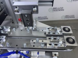 The custom dual-belt conveyor Bellco designed and built, gripping each ring terminal from both sides so every part travels at the same speed
