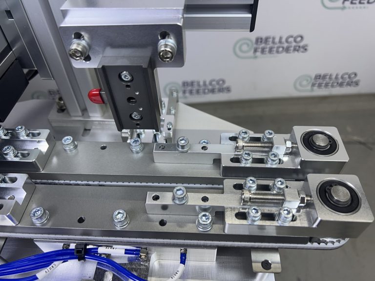 The custom dual-belt conveyor Bellco designed and built, gripping each ring terminal from both sides so every part travels at the same speed