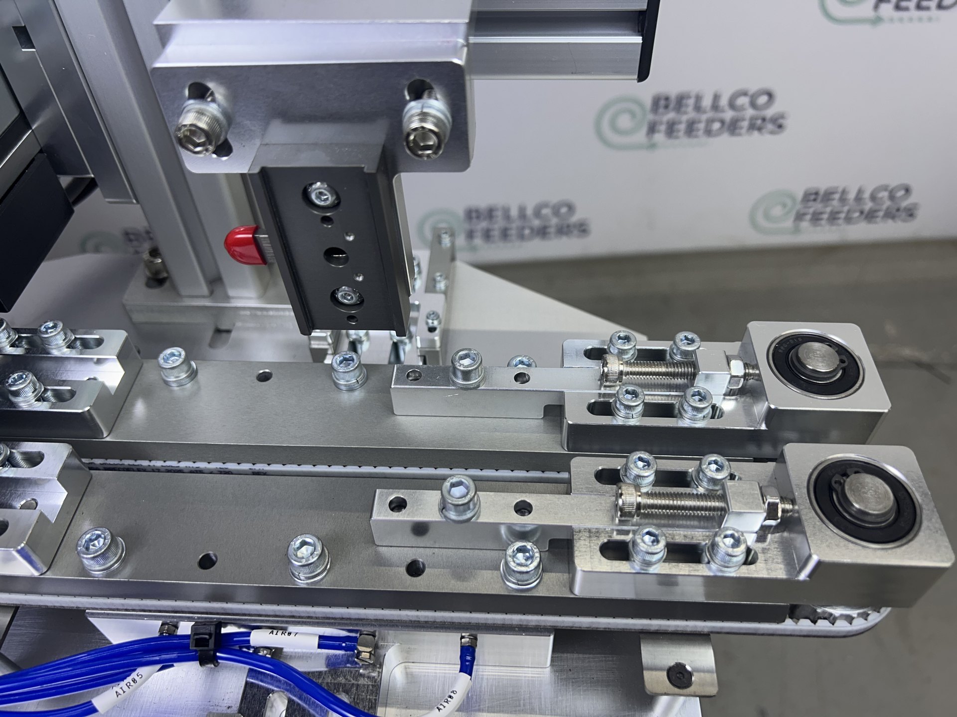 The custom dual-belt conveyor Bellco designed and built, gripping each ring terminal from both sides so every part travels at the same speed