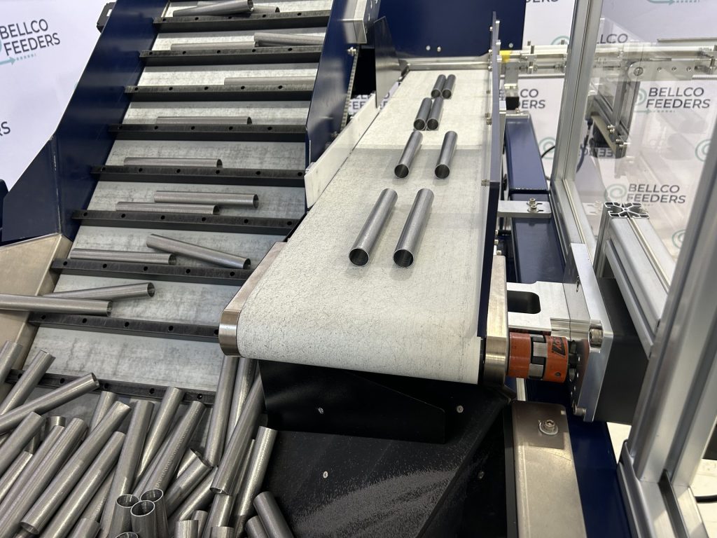 Steel pins arriving on the flat-belt outfeed of a Bellco cleated incline conveyor