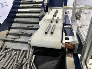 Steel pins arriving on the flat-belt outfeed of a Bellco cleated incline conveyor