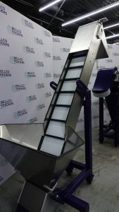Bellco elevating conveyor hopper with a stainless bulk bin feeding a cleated incline belt