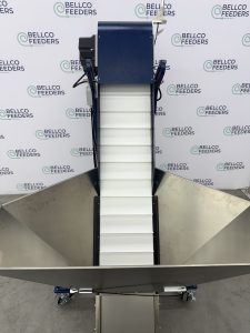 Bellco elevated conveyor hopper installed alongside a vibratory bowl feeder