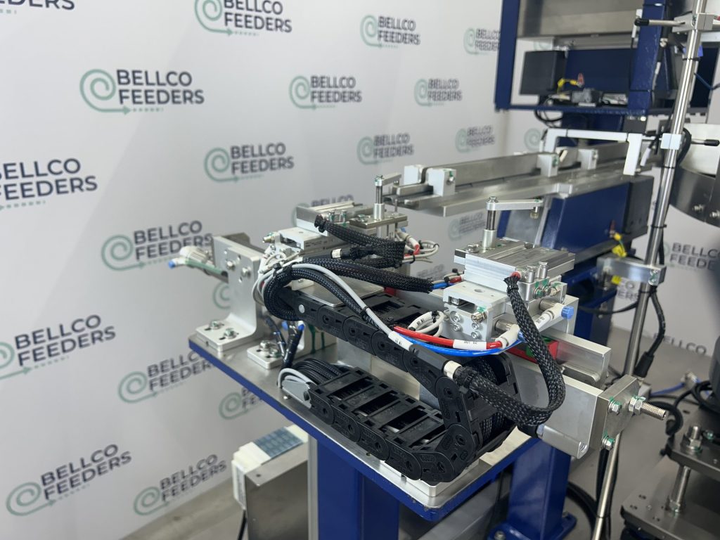Multi-stage pneumatic escapement built by Bellco, staging parts through two gates before the pick point