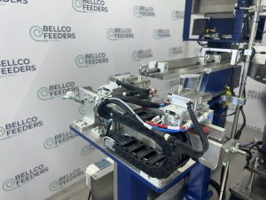 Multi-stage pneumatic escapement built by Bellco, staging parts through two gates before the pick point