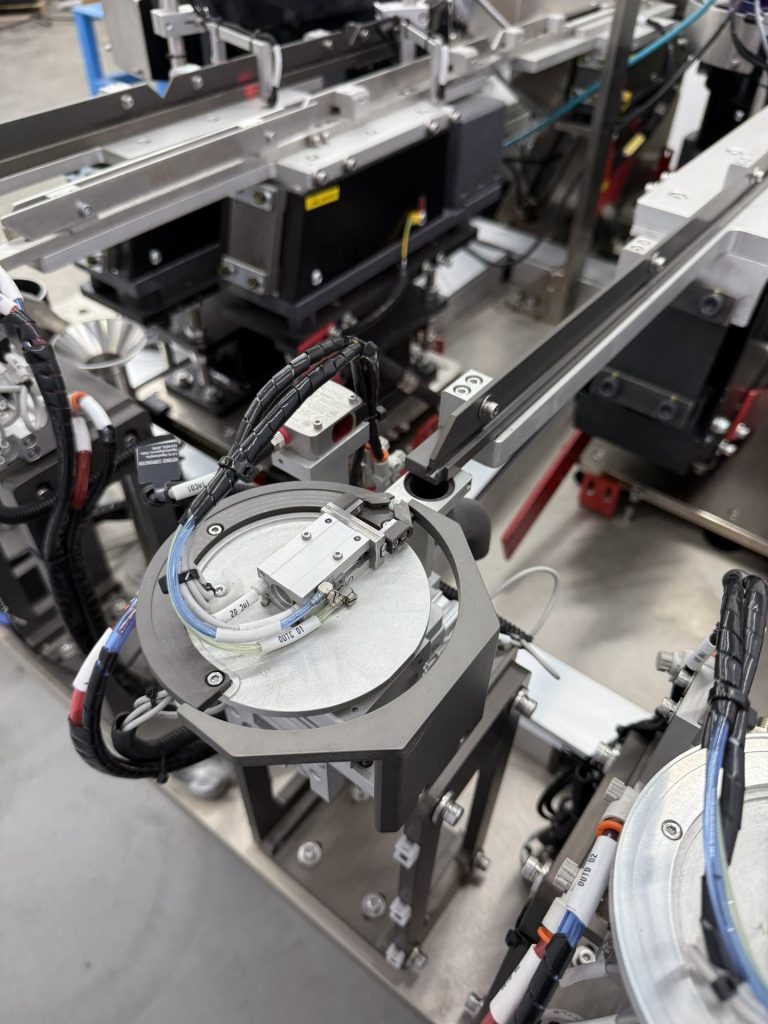 Bellco horizontal rotating escapement, which holds a singulated part in a fixed position for a robot to press out from below