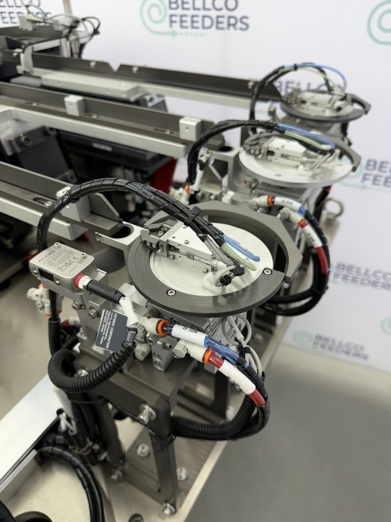 Two Bellco rotary escapements mounted side by side at the outfeed of a multi-bowl feeding cell