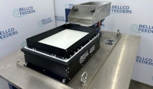Bellco Flex flexible feeder on a stainless work surface, with its backlit part platform and stainless refill hopper