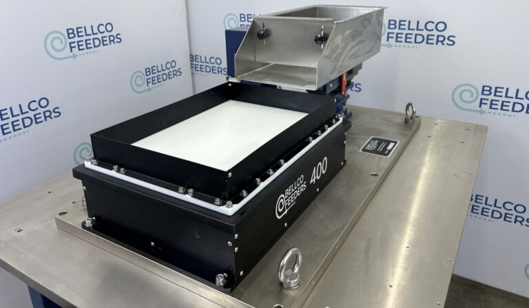 Bellco Flex flexible feeder on a stainless work surface, with its backlit part platform and stainless refill hopper
