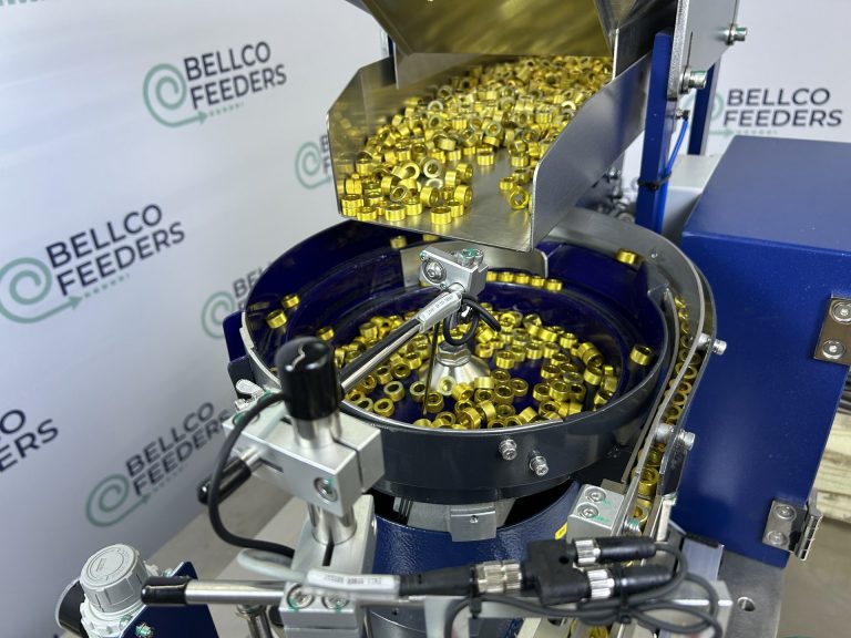 Bellco vibratory hopper discharging brass fittings into a bowl feeder for up to an hour of unattended running