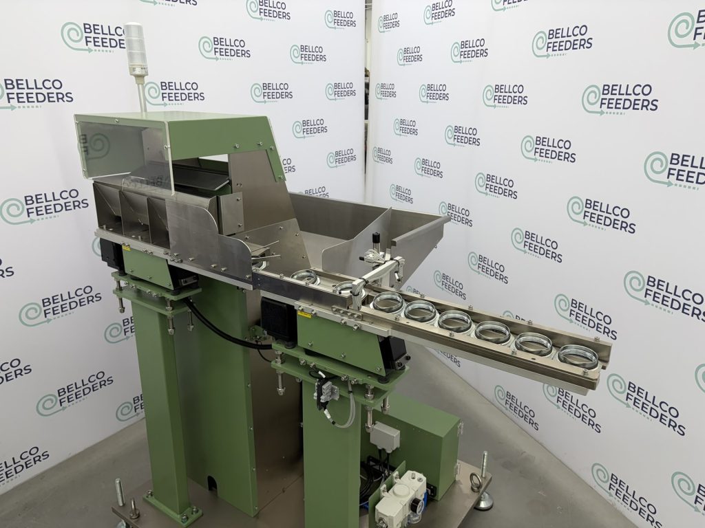 Bellco step feeder feeding steel flanges down its linear track toward a downstream packaging conveyor