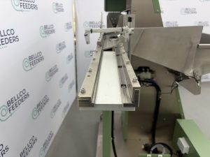 Close-up of the 550mm vibratory linear track on a Bellco step feeder, orienting steel flanges flat-side down