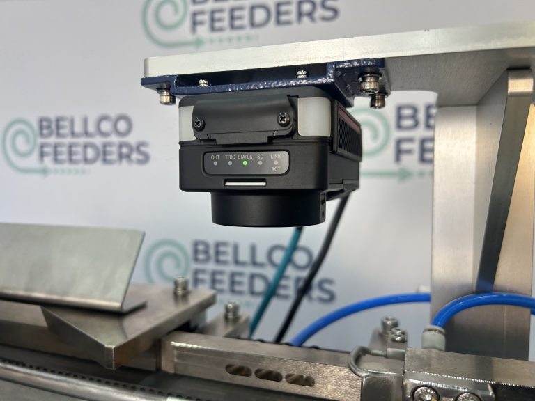 Keyence vision camera mounted above a Bellco linear track, inspecting each part in flight to confirm its orientation