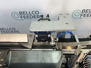 Vision camera and blow-off nozzle over a Bellco track, set up to reject any part running the wrong way round