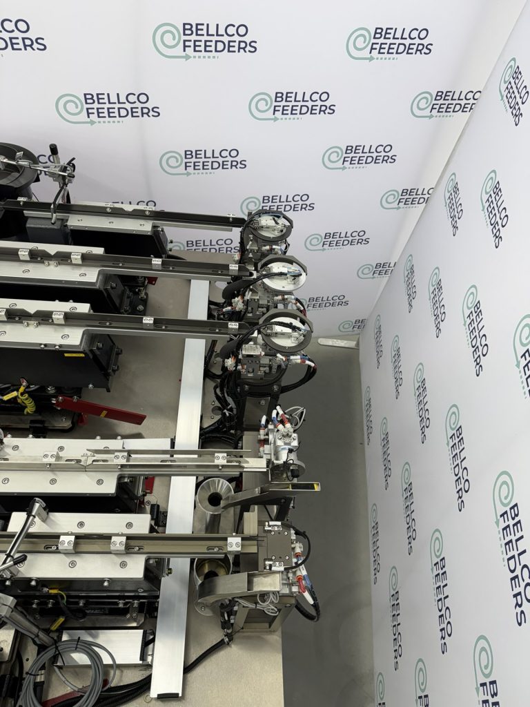 Multi-track Bellco feeding cell with rotary escapements presenting parts for robotic pick-up