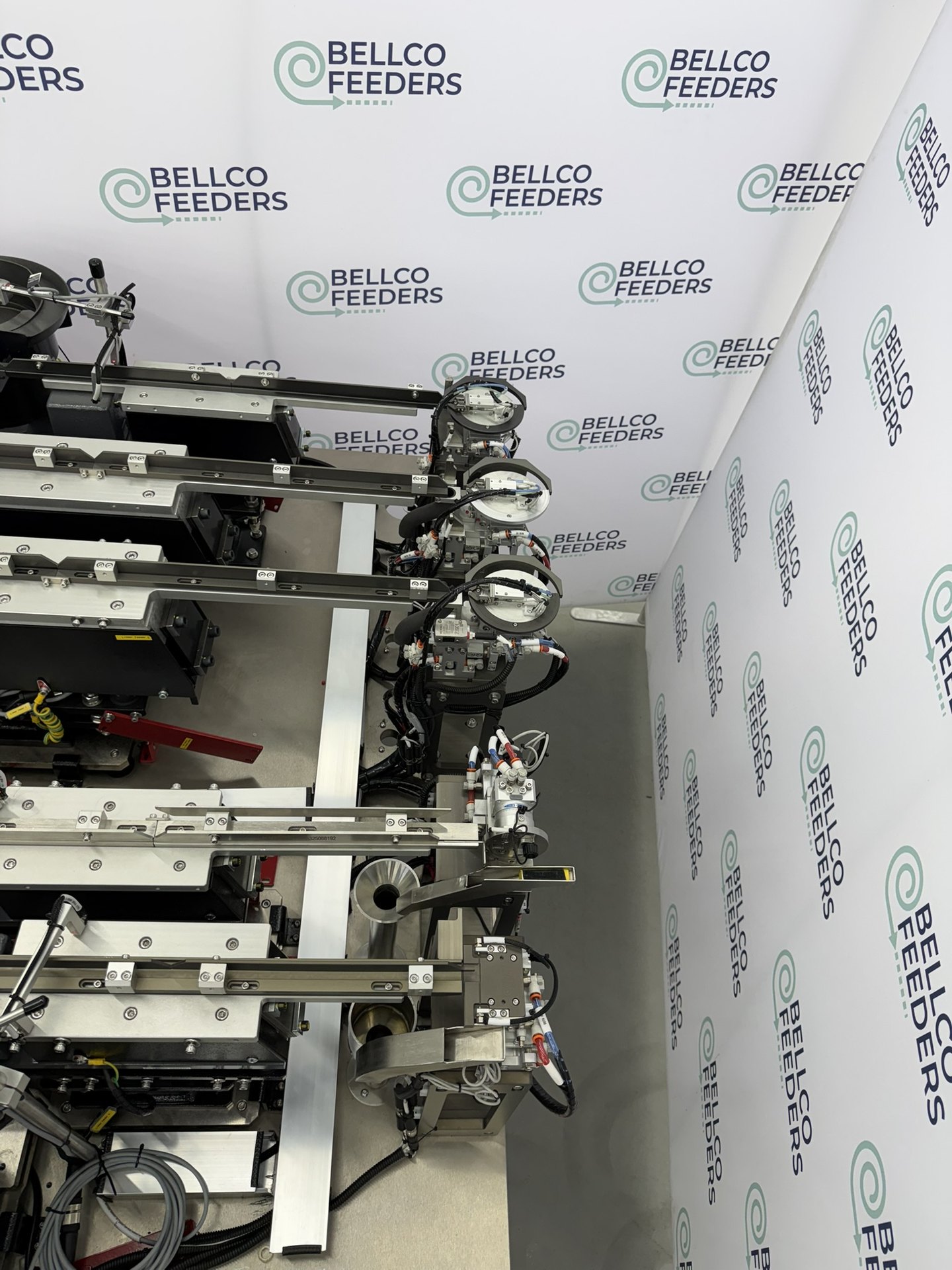 Multi-track Bellco feeding cell with rotary escapements presenting parts for robotic pick-up