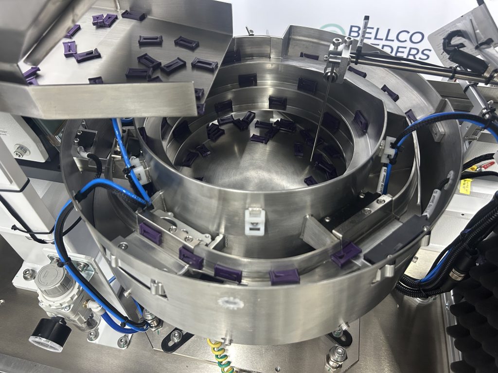 view of bulk hopper feeding plastic clips into vibratory bowl, using a keyence sensor for optimal flow