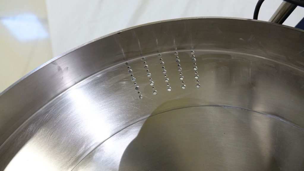 Interior of a polished 316 stainless feeder bowl with tablet parts spaced along the track