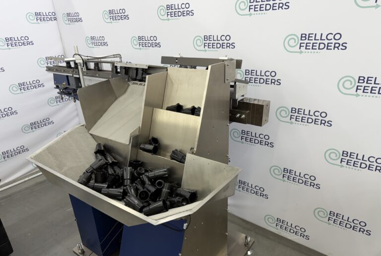 Stainless steel step feeder loaded with black cylindrical parts