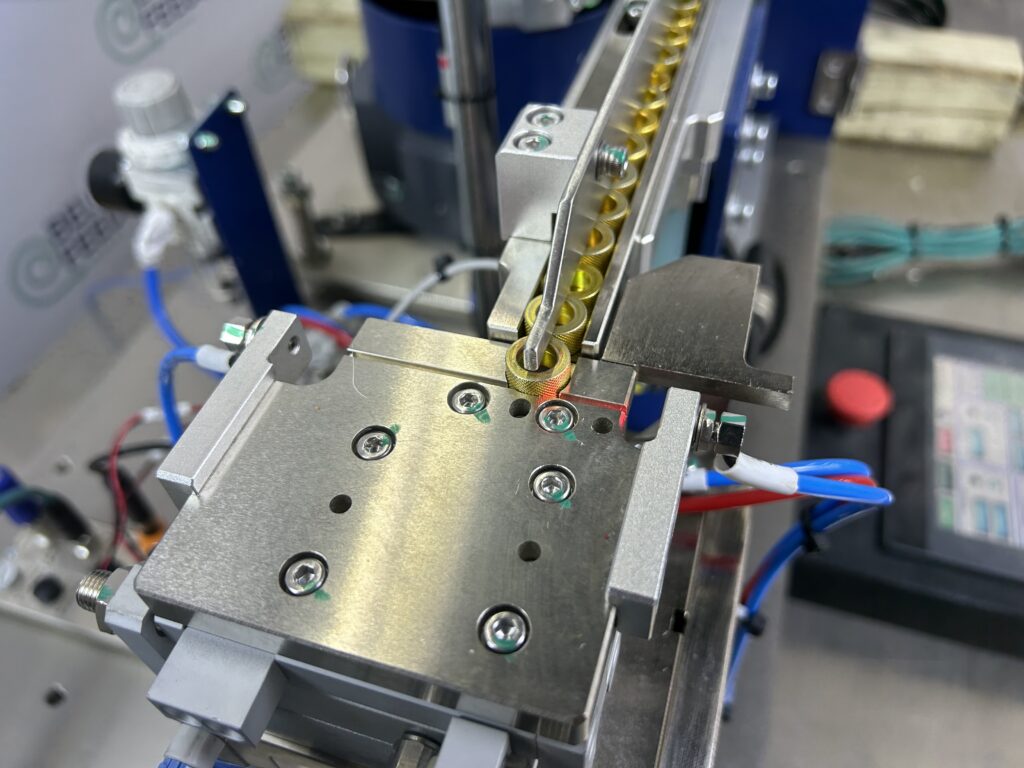 Escapement indexing coiled spring parts off an inline feed track