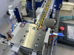 Escapement indexing coiled spring parts off an inline feed track